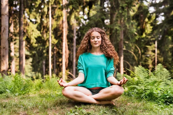 Hermosa chica practica yoga en el bosque matutino. — Foto de Stock