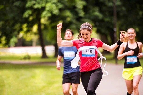 Mujer joven corriendo entre la multitud cruzando la línea de meta . — Foto de Stock