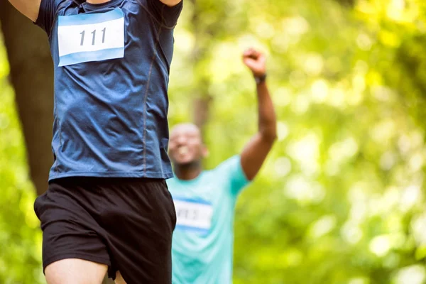 Jóvenes corredores irreconocibles cruzando la línea de meta . — Foto de Stock