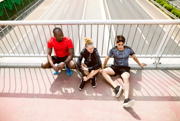 Young runners in the city resting on a bridge. — Stock Photo, Image