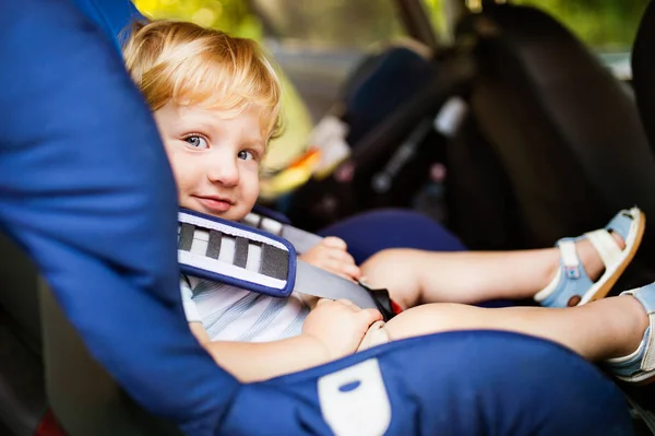 Mały chłopiec siedzi w fotelika w samochodzie. — Zdjęcie stockowe
