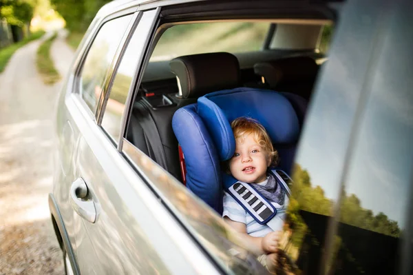Liten pojke sitter i bilstolen i bilen. — Stockfoto