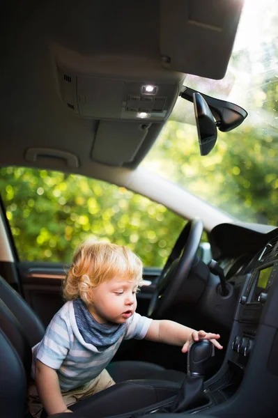 Liten pojke spelar i bilen, låtsas köra det. — Stockfoto