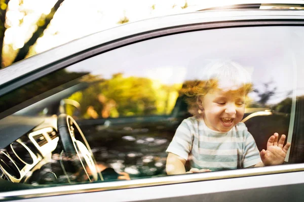 Mały chłopiec w samochodzie, patrząc z okna, macha. — Zdjęcie stockowe