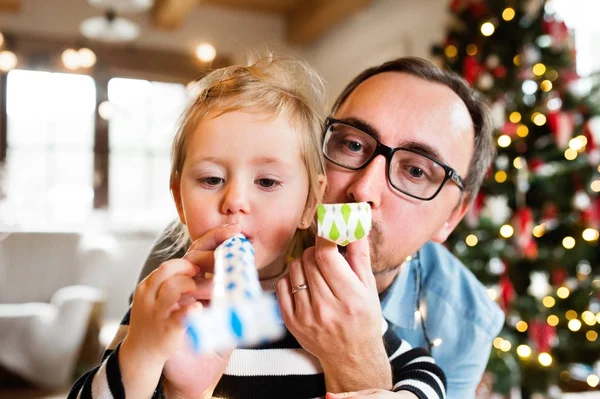 Pai com filha na época do Natal soprando apitos festa . — Fotografia de Stock