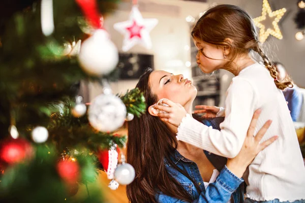 Young mother with daughter decorating Christmas tree together. — Stock Photo, Image