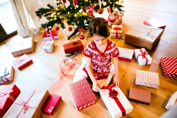 Little girl under the Christmas tree opening presents. — Stock Photo, Image