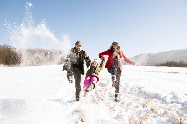 Vater und Mutter mit ihrer Tochter beim Spielen im Schnee. — Stockfoto