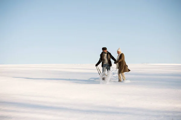 Mooie hoge paar op een wandeling trekken sleden, winterdag. — Stockfoto