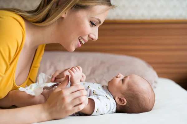 Madre con su hijo recién nacido acostado en la cama — Foto de Stock