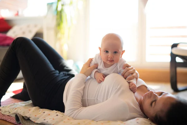 Mother lying on the floor holding her cute baby son — Stock Photo, Image