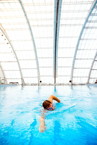 Man swimming in an indoor swimming pool.