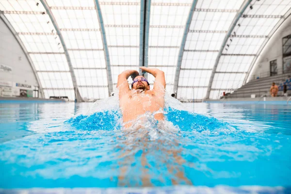 Homem nadando em uma piscina interior . — Fotografia de Stock