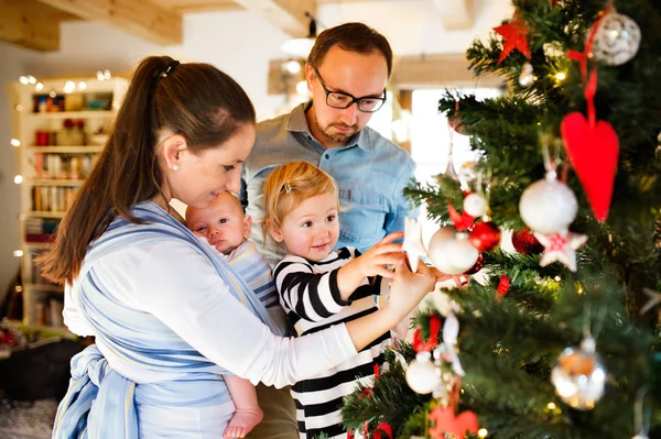 Jonge ouders met twee kinderen bij Kerstmis. — Stockfoto