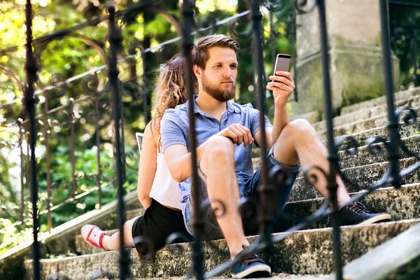 Jovem casal com smartphones sentados nas escadas da cidade . — Fotografia de Stock