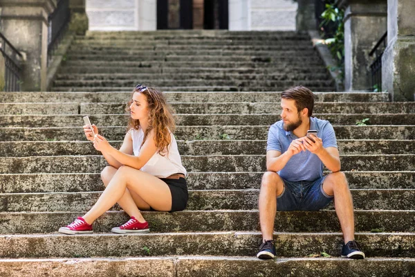 スマート フォン町の階段に座っている若いカップルします。. — ストック写真