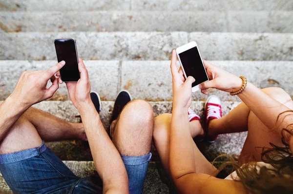 Casal irreconhecível com smartphones sentados em escadas na cidade — Fotografia de Stock