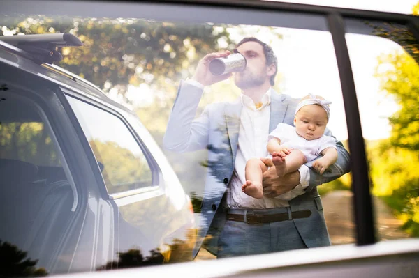 Hombre cargando a su bebé, bebiendo café . — Foto de Stock