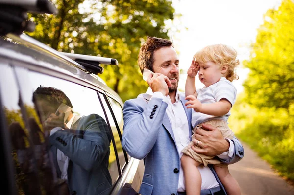 그의 작은 소년과 차에서 스마트폰 젊은 아버지. — 스톡 사진