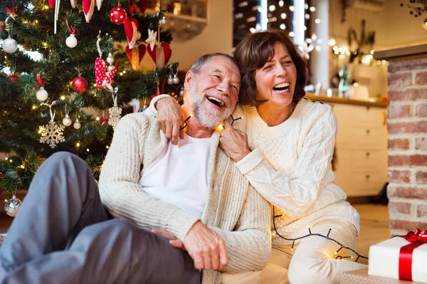 Äldre par framför julgranen med presenter. — Stockfoto