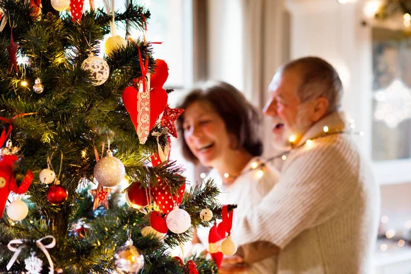 Casal sênior olhando para a árvore de Natal em casa . — Fotografia de Stock