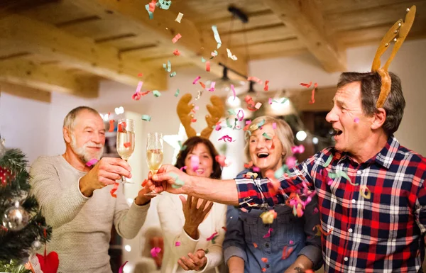 Senior vänner med konfetti och champagne på julgranen — Stockfoto