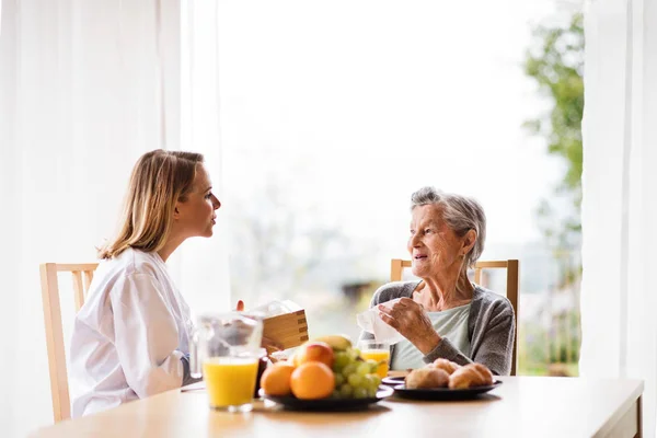 Visitante de salud y una mujer mayor durante la visita a casa . — Foto de Stock