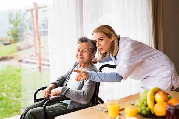 Медицинский посетитель и пожилая женщина во время посещения дома . — стоковое фото