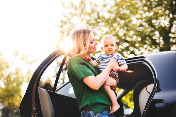 Молодая мать со своим маленьким мальчиком, стоящим у машины . — стоковое фото