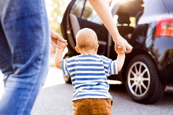 Ung mor med sin lilla baby pojke walking av bilen. — Stockfoto