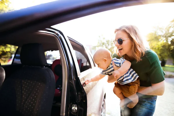 Jovem mãe com seu filhinho de pé junto ao carro . — Fotografia de Stock