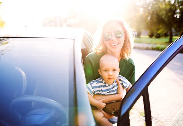 Ung mor med sin lilla baby pojke att få in i bilen. — Stockfoto