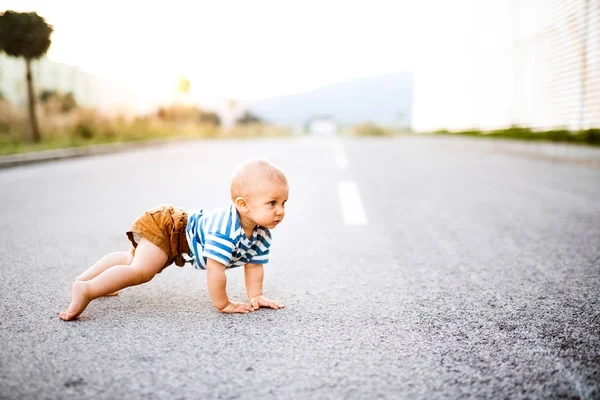 Pequeño niño arrastrándose afuera en el camino . — Foto de Stock
