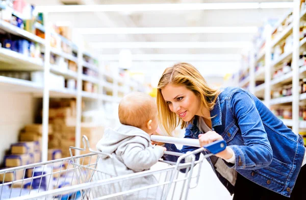 Joven madre con su pequeño bebé en el supermercado . —  Fotos de Stock