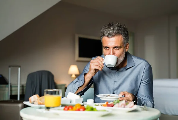 Maduro hombre de negocios desayunando en una habitación de hotel . — Foto de Stock