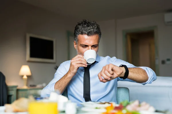 Homem de negócios maduro tomando café da manhã em um quarto de hotel . — Fotografia de Stock