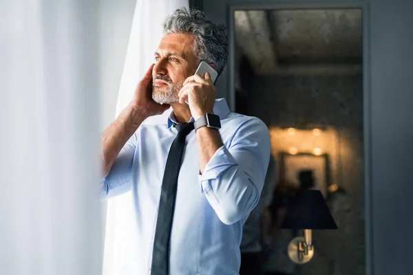Uomo d'affari maturo con smartphone in una camera d'albergo . — Foto Stock
