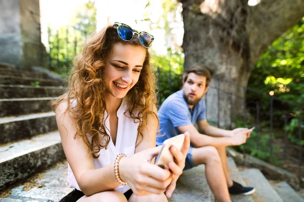 Jovem casal com smartphones sentados nas escadas da cidade . — Fotografia de Stock