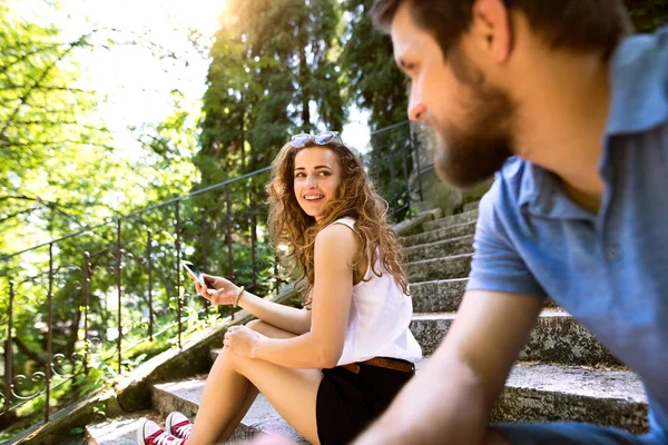 Jovem casal com smartphone sentado em escadas na cidade . — Fotografia de Stock