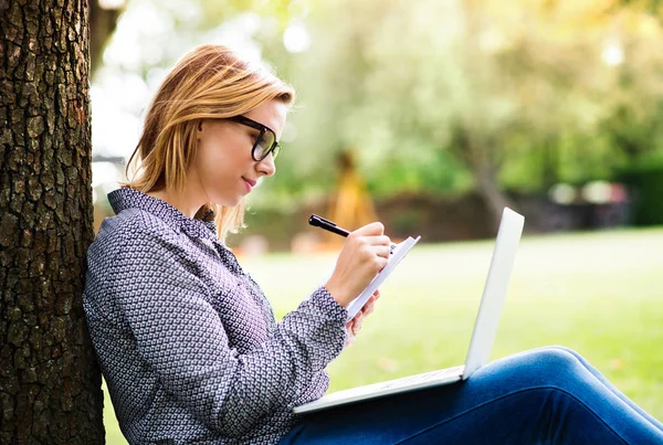 Mujer joven con un portátil que estudia al aire libre . — Foto de Stock