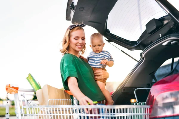 Madre con bambino mettere shopping nel retro della macchina . — Foto Stock