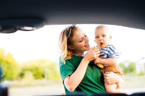 Молодая мать со своим маленьким мальчиком, стоящим у машины . — стоковое фото