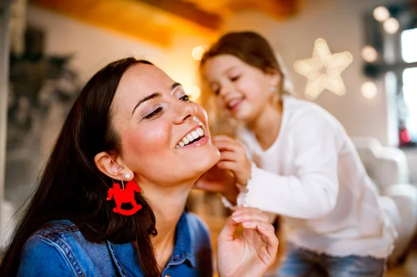 Junge Mutter mit Tochter schmückt gemeinsam Weihnachtsbaum. — Stockfoto