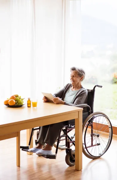 Mujer mayor en silla de ruedas con tablet en casa . —  Fotos de Stock