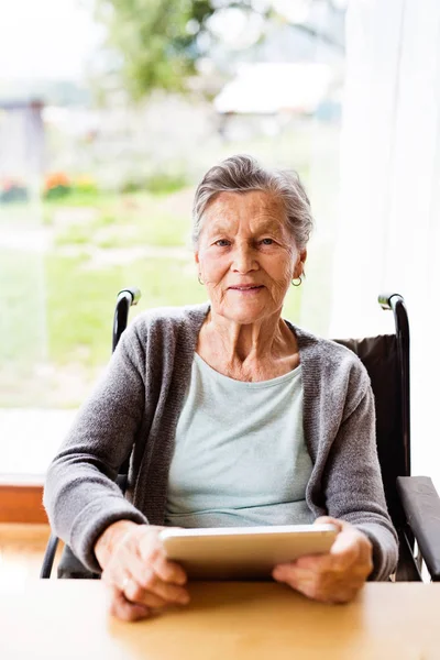Senior Kvinna i rullstol med tablett hemma. — Stockfoto