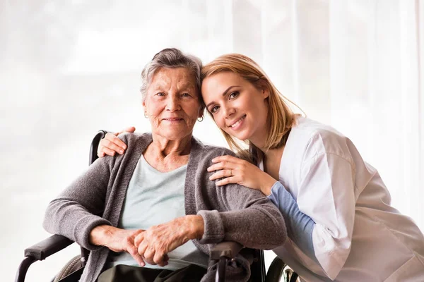 Odwiedzający zdrowie i starsza kobieta podczas wizyty domowej. — Zdjęcie stockowe