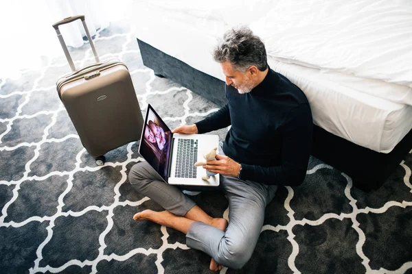 Érett üzletember, a laptop a szállodai szobában. — Stock Fotó
