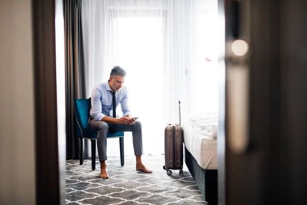 Érett üzletember smartphone egy szállodai szobában. — Stock Fotó