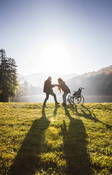 Senior paar met rolstoel in de herfst natuur. — Stockfoto