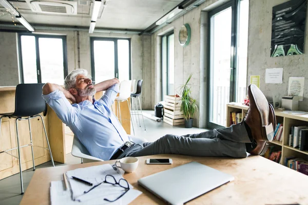 Pensativo homem de negócios maduro com smartphone no escritório . — Fotografia de Stock